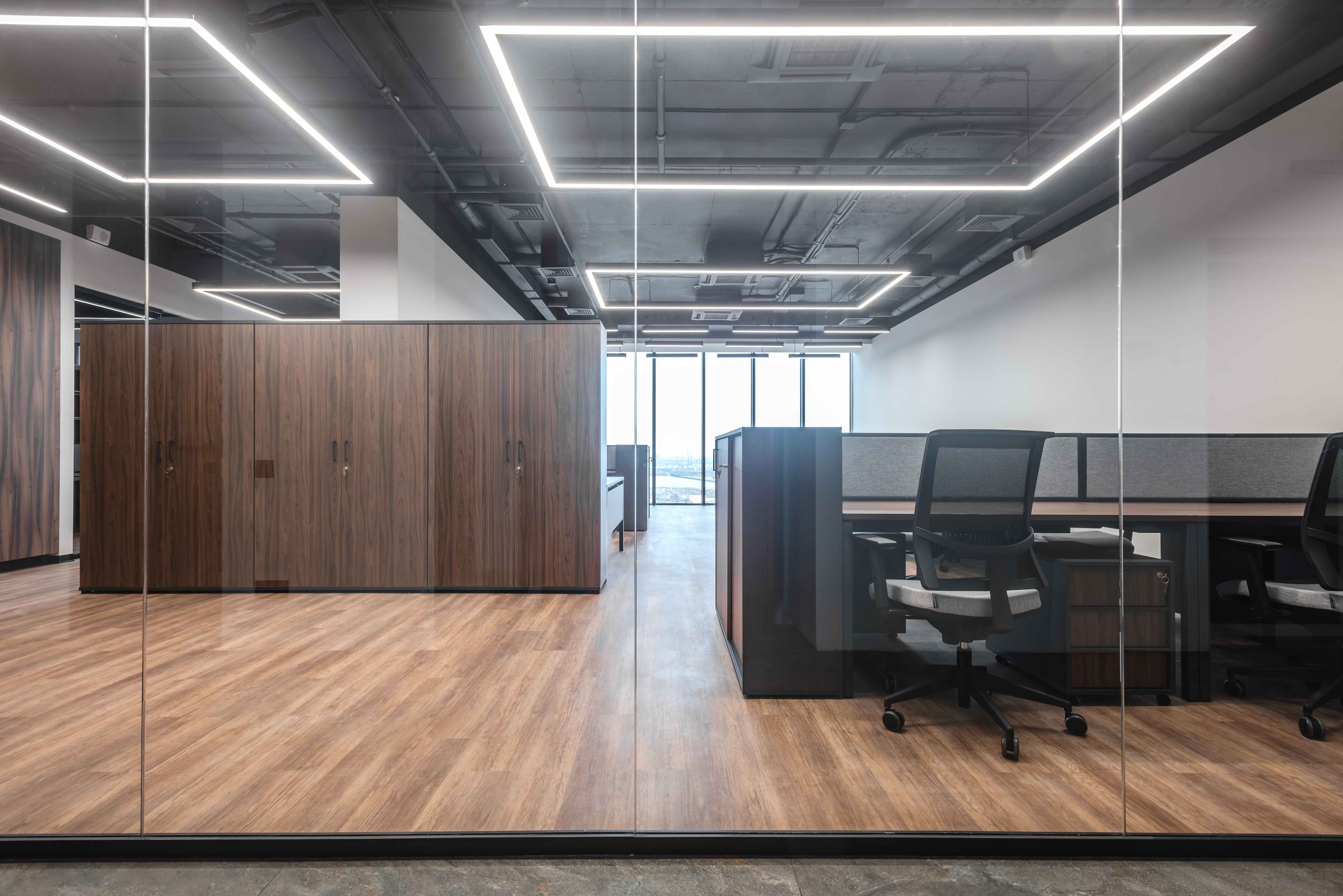 Contemporary office with glass partitions and walnut storage